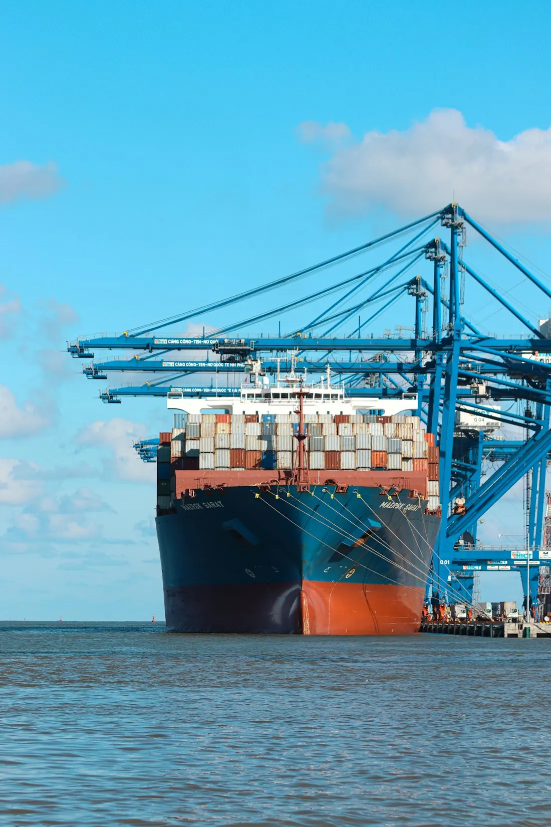 Container ship being unloaded under port cranes